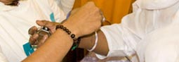 Someone times the rakhi bracelet onto Amma's wrist