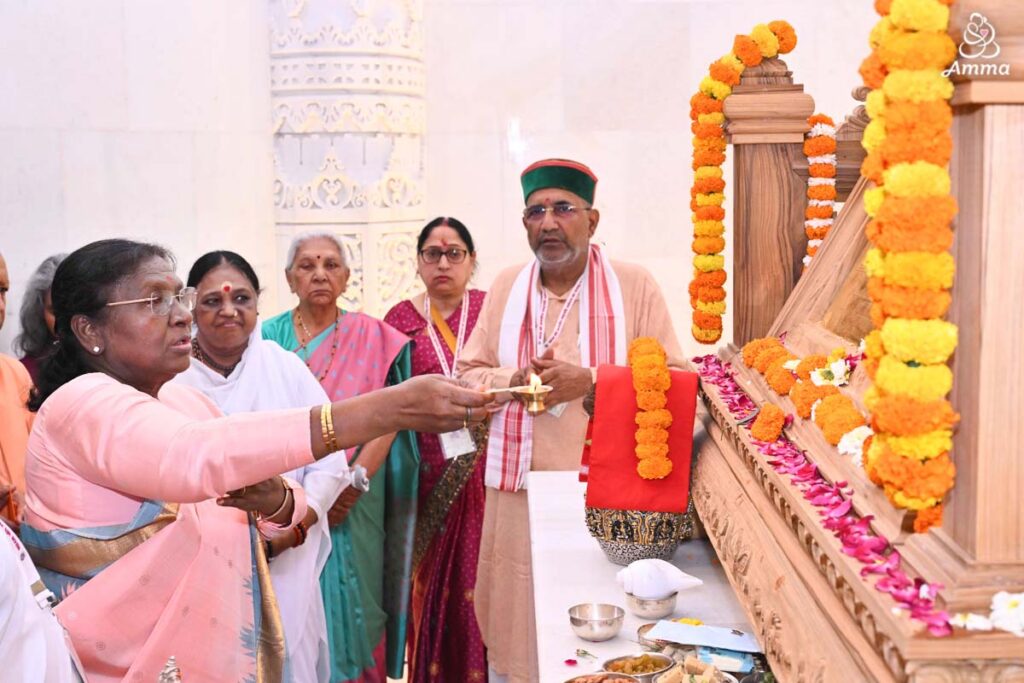 The President of India performs arati to the yantra beside Amma