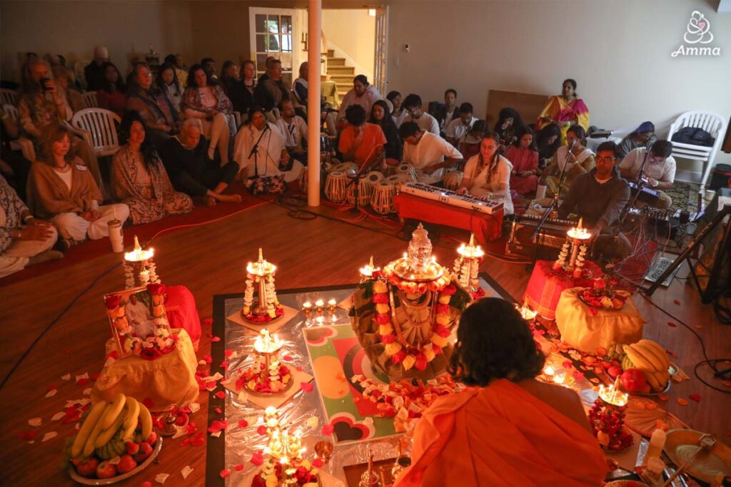 a pujari surrounded with oil lamps and flowers