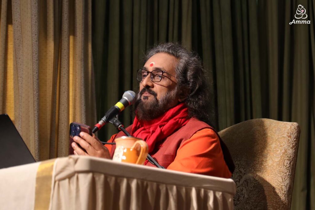 a swami speaks at a microphone