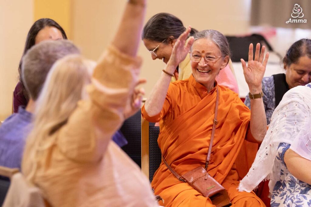 A swamini smiles and laugh with a happy crowd of people