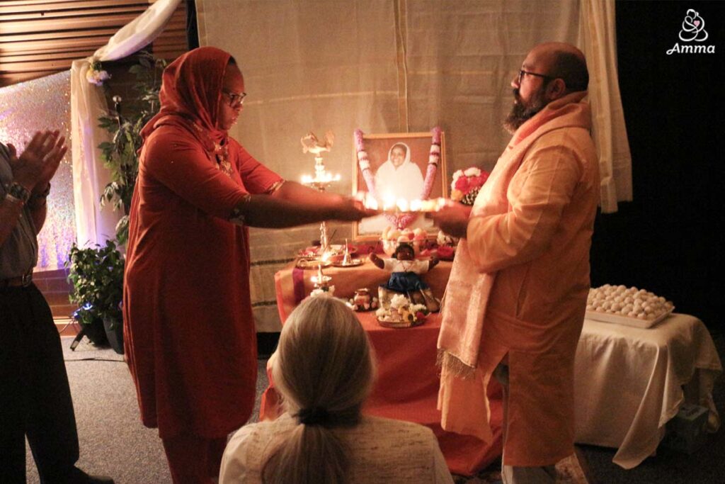 waving camphor lamps to an image of Amma