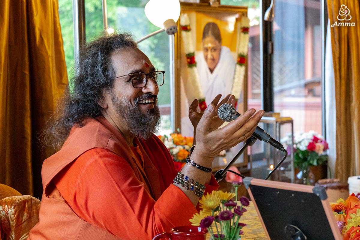 A swami smiles as he speaks to a gathering