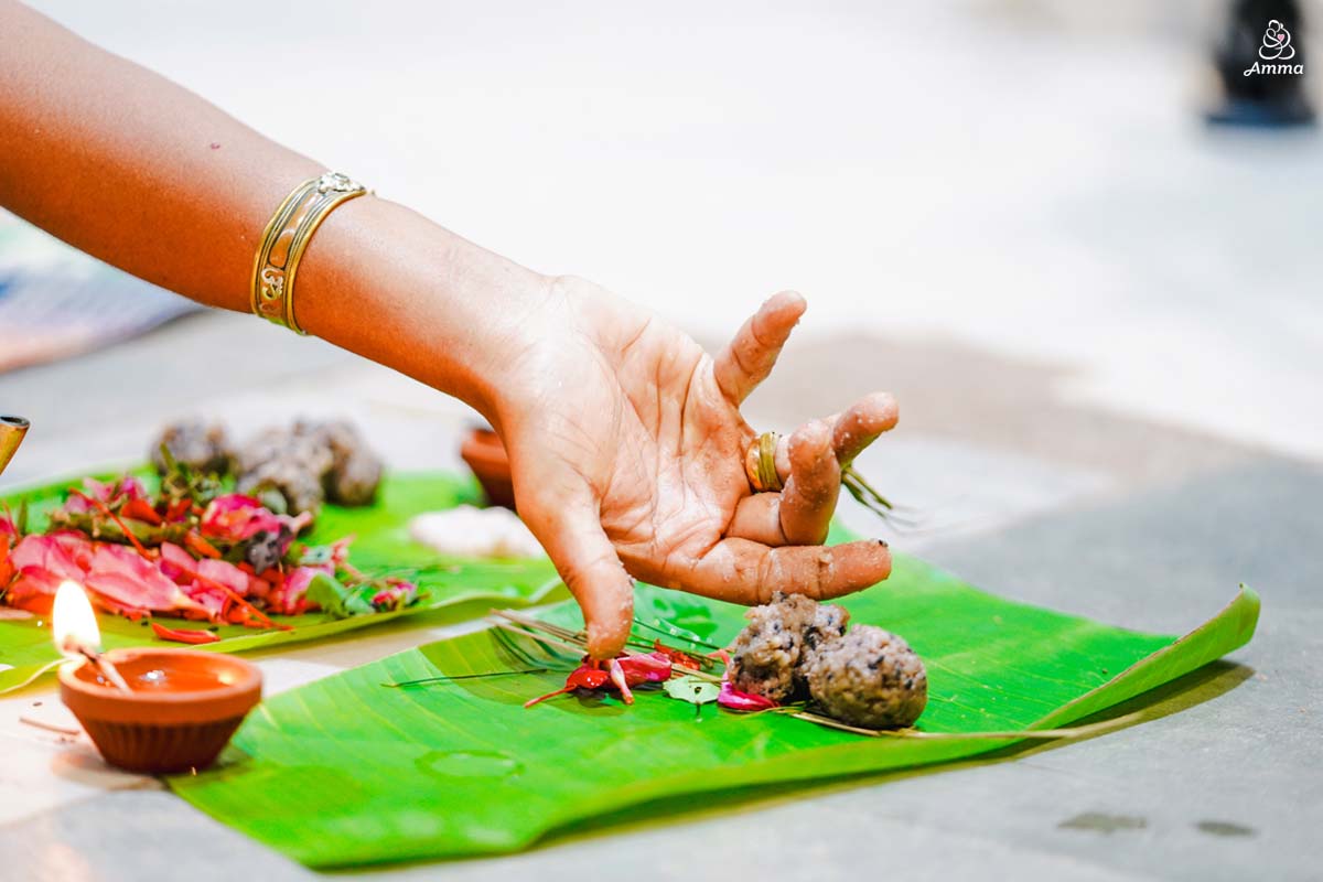 A hand offers rice balls upon a banana leaf