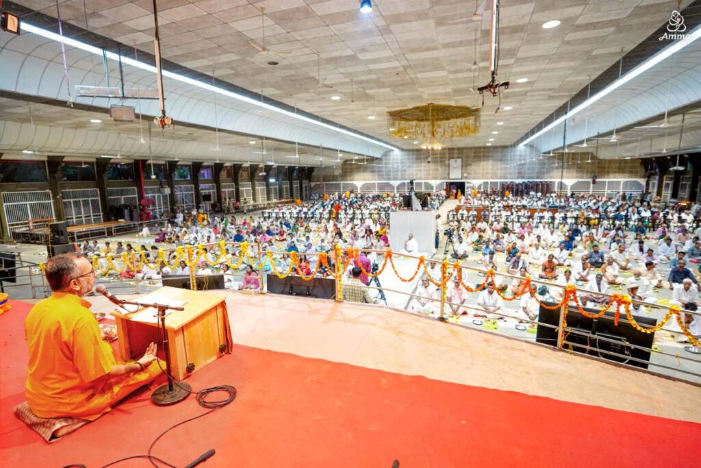 A brahmachari in yellow addresses the gathering