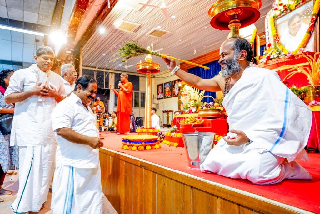 A pujari sprinkles water on a man