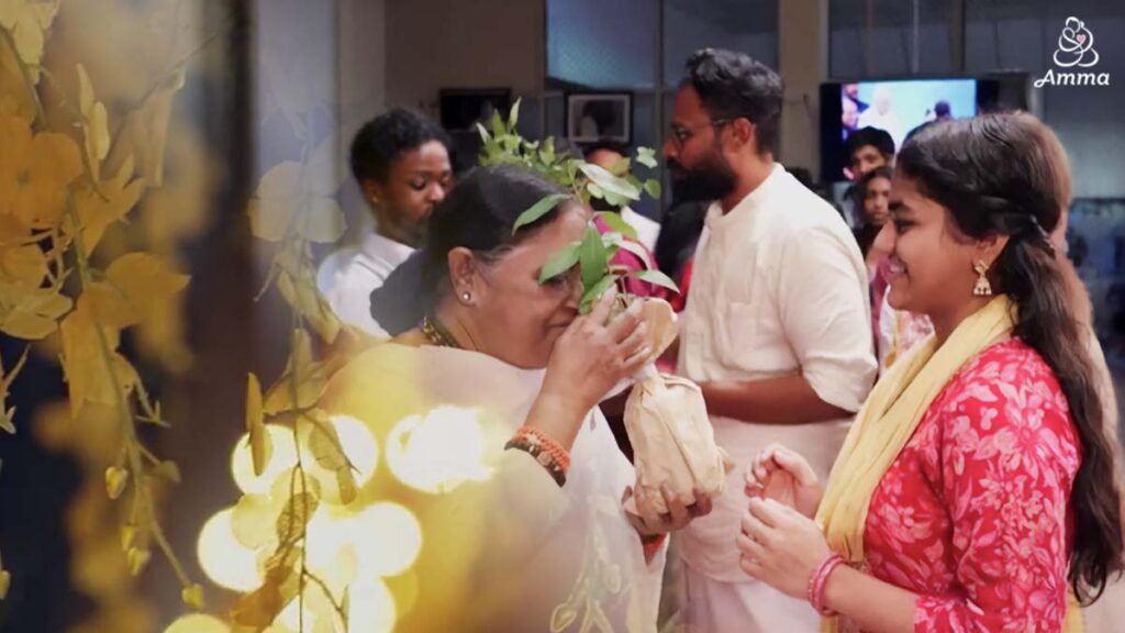 Amma gives a sapling to a young woman