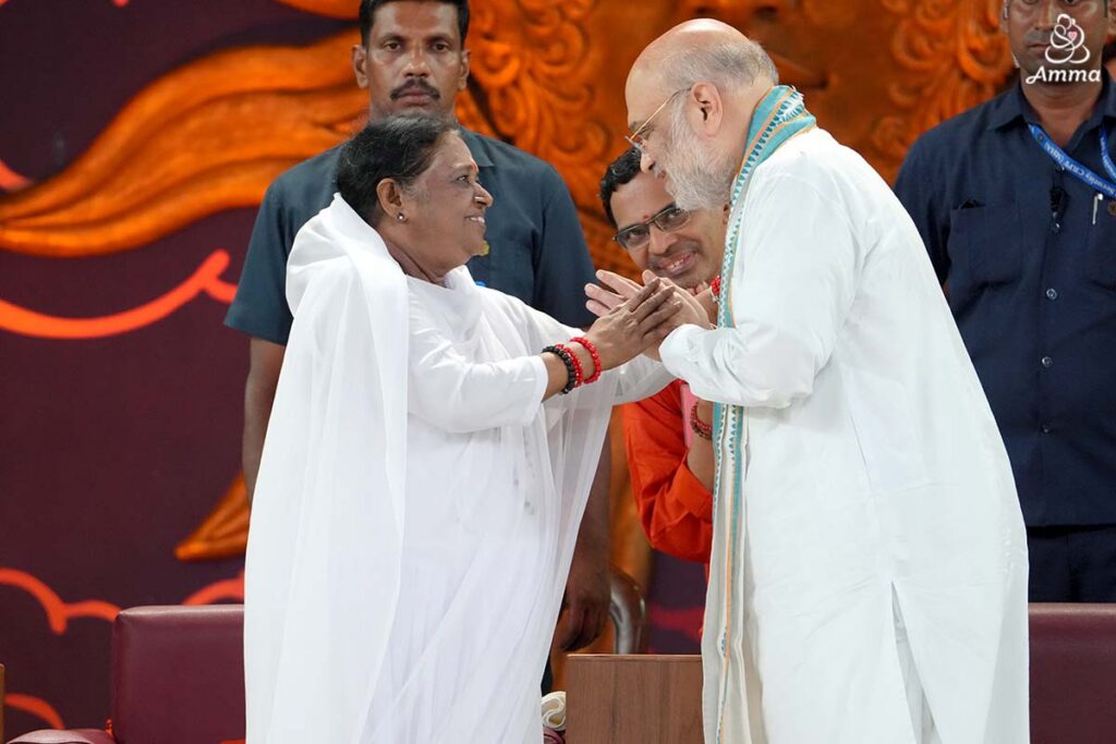 Amma looks a man in the eys and holds his hand