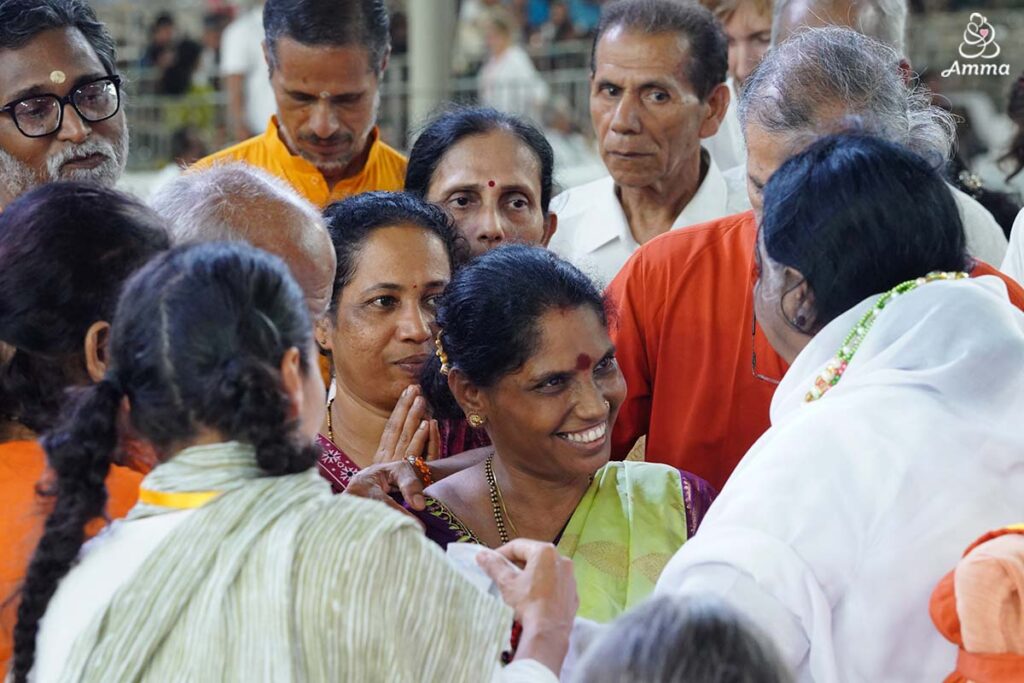 A woman enters Amma's arms for an embrace, darshan