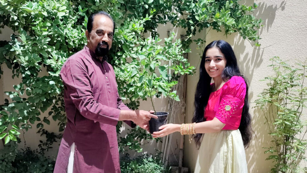 Father and daughter hold a tulsi plant