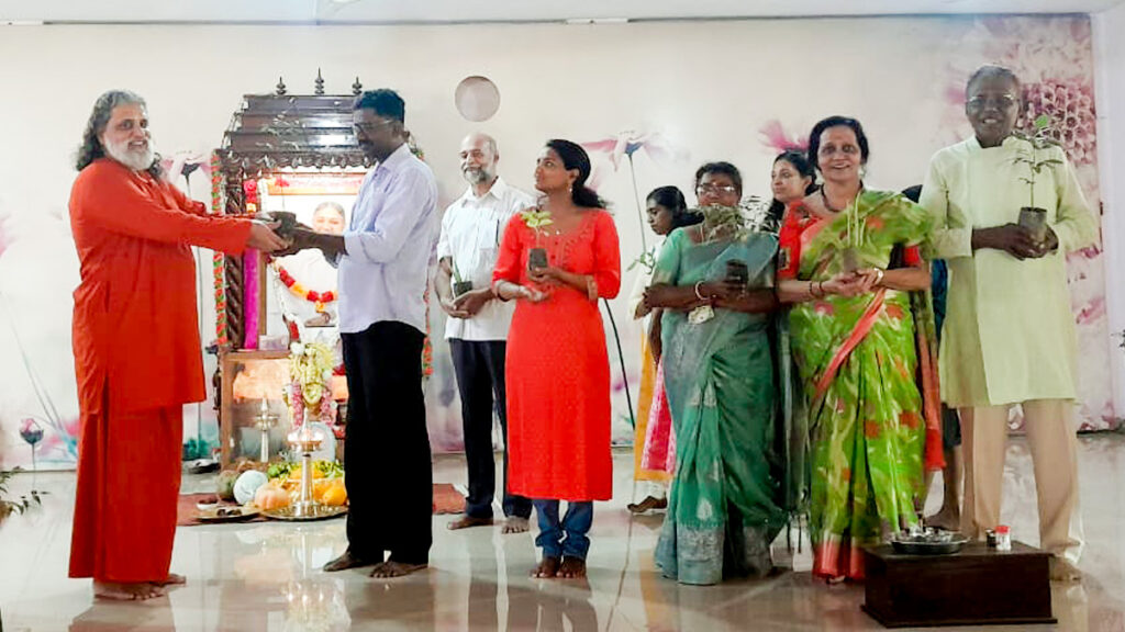 Swami and devotees hold plants