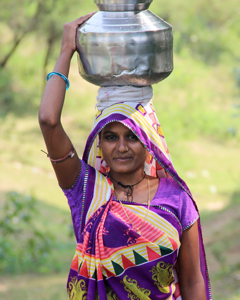 a woman carries a metal pot