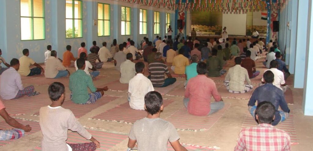 prisoners meditate in a big hall